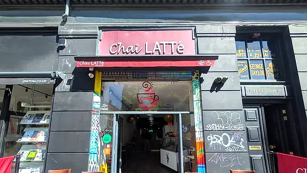 Chai Latte shopfront on Stevenson Square, red sign above an open door with pavement tables outside.